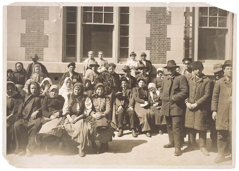 Gruppe af indvandrere uden for en bygning på Ellis Island, USA